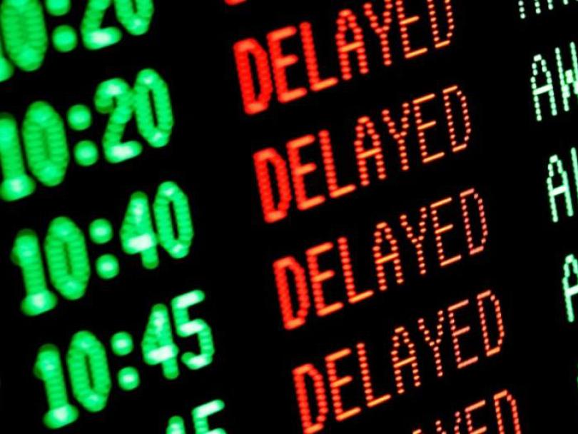 Electronic departures board showing multiple scheduled times marked as “DELAYED” in red text.