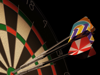 Three darts grouped closely in the center area of a dartboard against a dark background.
